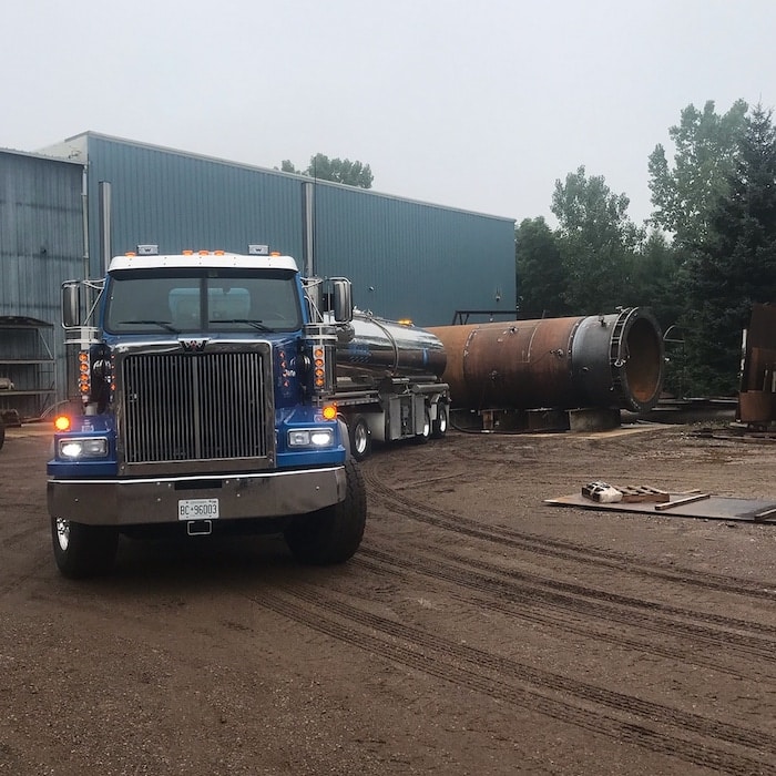 Bulk water truck beside industrial tanks